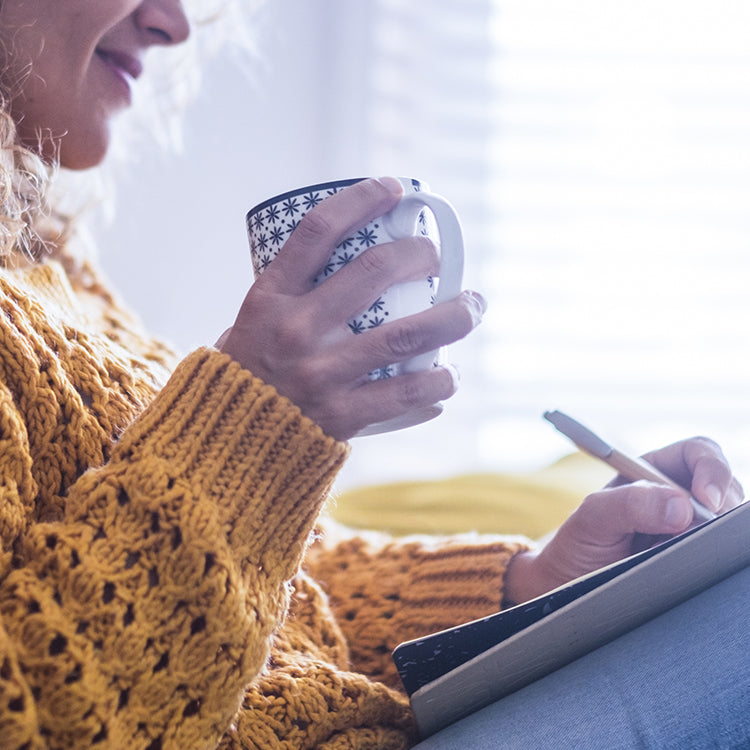 Woman drinking coffee and writing in journal