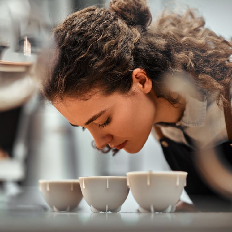 A woman smelling different brewed coffee samples